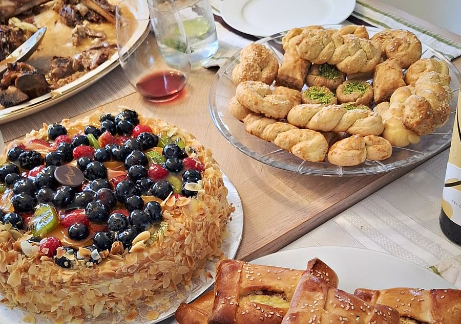 A shared table with fruit and almond cake, twisted pastries and wine