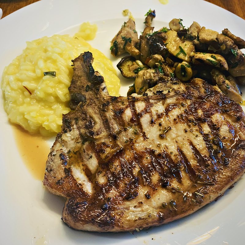 Grilled pork chop with saffron risotto and sautéed mushrooms
